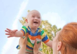 criança com síndrome de down feliz e sua mãe