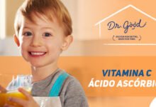 Menino loiro com olhos azuis segurando um copo com um líquido laranja, logo Dr. Good no canto da arte, ao lado do menino está escrito "VITAMINA C ÁCIDO ASCÓRBICO"